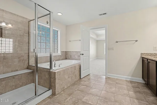 a spacious bathroom with a granite countertop sink a mirror and a shower