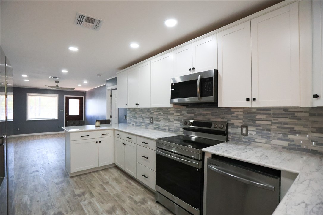 700 North Cameron Street Alice, TX 78332 - Photo 4 of 15 a kitchen with granite countertop a sink and a stove top oven with wooden floor