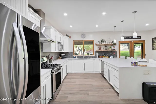 a large kitchen with stainless steel appliances sink a stove and cabinets