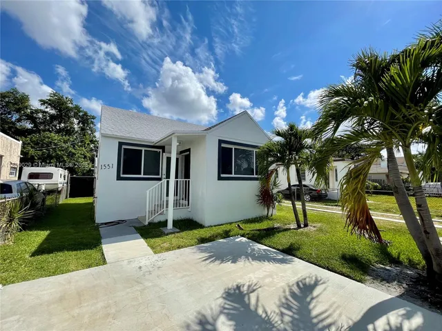 a front view of a house with garden and trees
