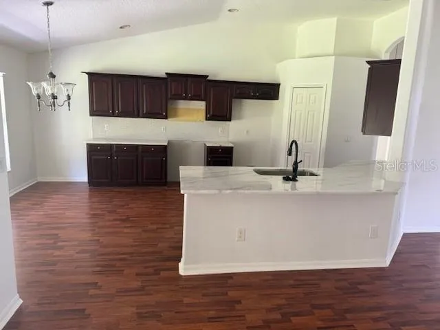 a view of a kitchen with kitchen island a sink wooden floor and a refrigerator