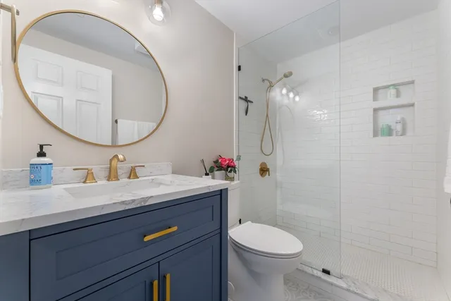 a bathroom with a granite countertop toilet sink mirror and vanity