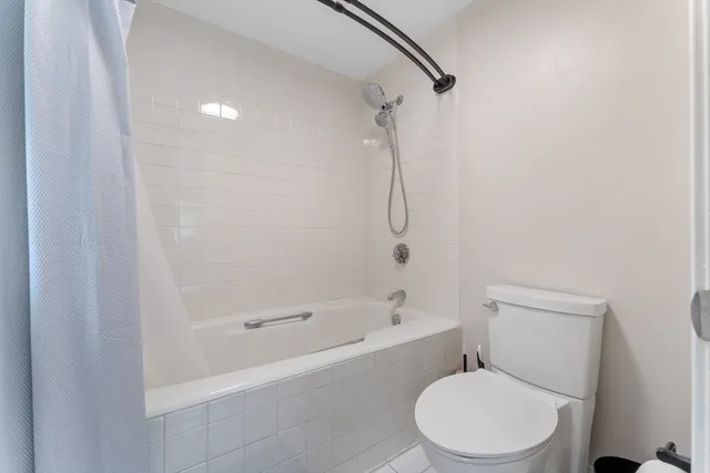 a white toilet and tub sitting next to a bathroom sink