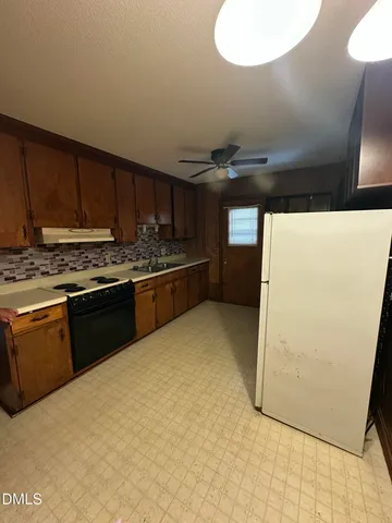 a kitchen with stainless steel appliances a refrigerator a sink a stove and white cabinets