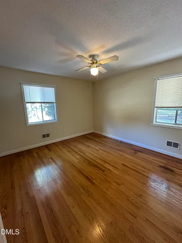 a view of empty room with wooden floor and fan