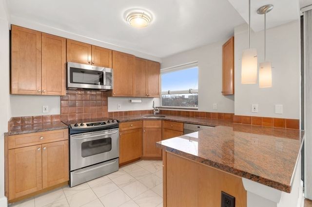 a kitchen with granite countertop a stove top oven microwave and cabinets