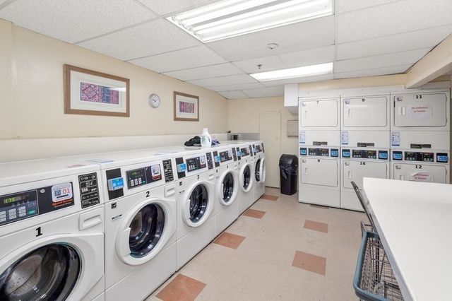 a view of a kitchen with stainless steel appliances granite countertop a white stove top oven a sink dishwasher and white cabinets