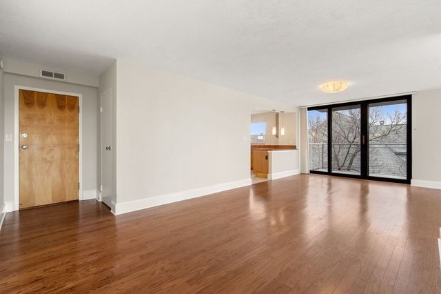 an empty room with wooden floor cabinet and windows