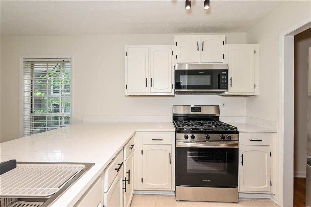201 Lenox Way Northeast Atlanta, GA 30324 - Photo 6 of 15 a kitchen with stainless steel appliances a stove a microwave and cabinets
