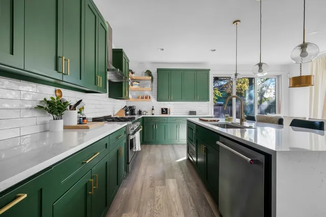 a kitchen with kitchen island granite countertop a sink a counter top space stainless steel appliances and cabinets