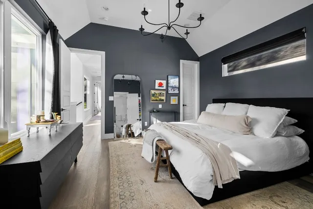 a bedroom with a bed chandelier and a window