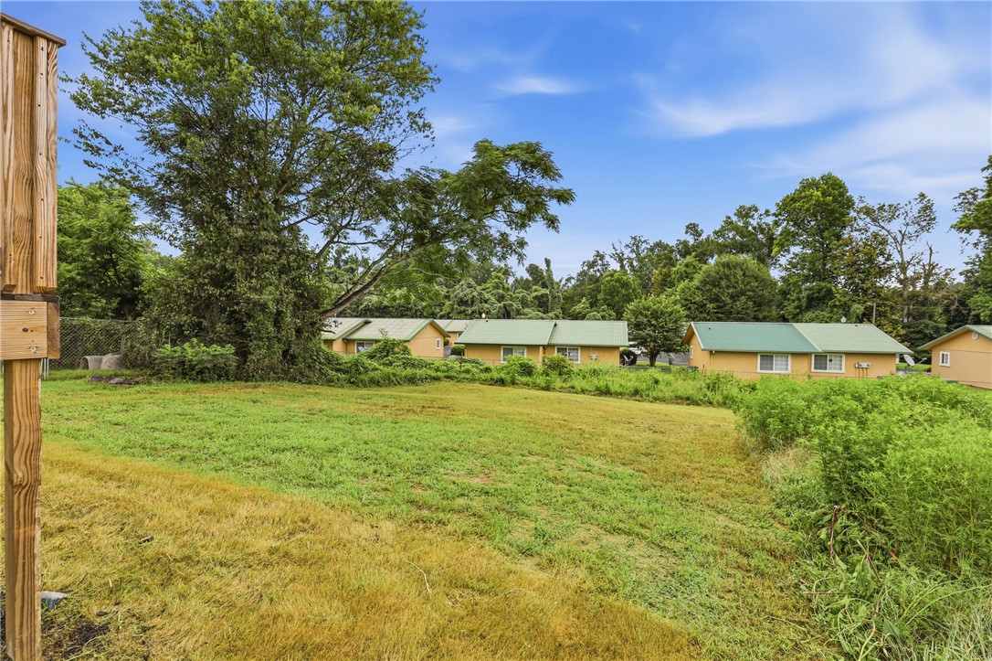 403 Tribble Street Seneca, SC 29678 - Photo 27 of 37 A verdant lot with mature trees offers a canvas for a future dwelling, set against a backdrop of single-story residences.