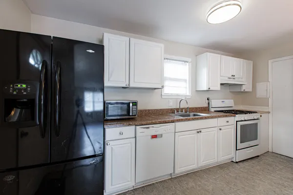 a kitchen with a sink dishwasher a refrigerator and cabinets