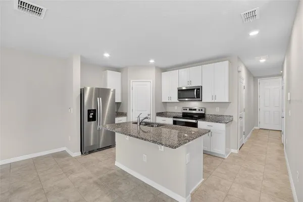 a large white kitchen with kitchen island a stove a sink a refrigerator and white cabinets