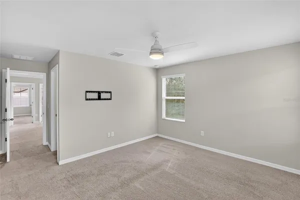 an empty room with a ceiling fan and a window