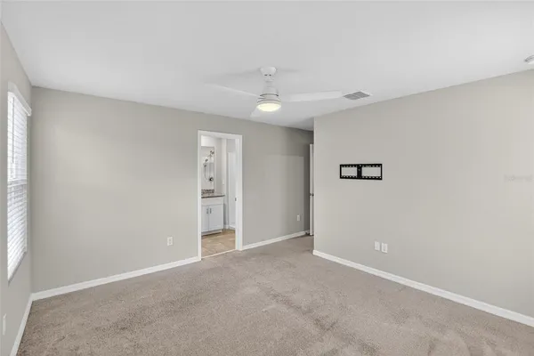 an empty room with a window and ceiling fan