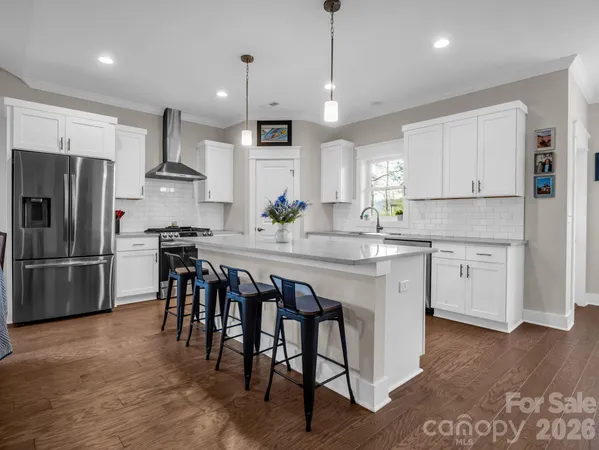 a kitchen with stainless steel appliances a table chairs refrigerator and microwave