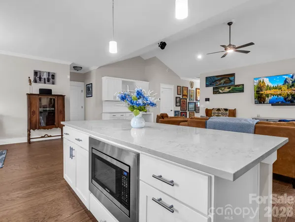 a kitchen with stainless steel appliances a sink a stove a refrigerator cabinets and living room view