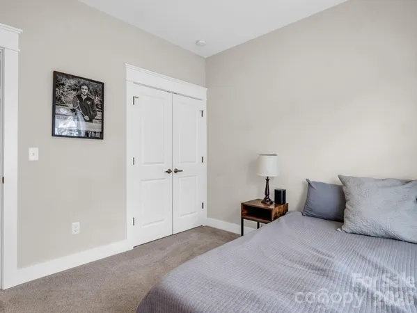 a bedroom with a bed and a lamp on dresser