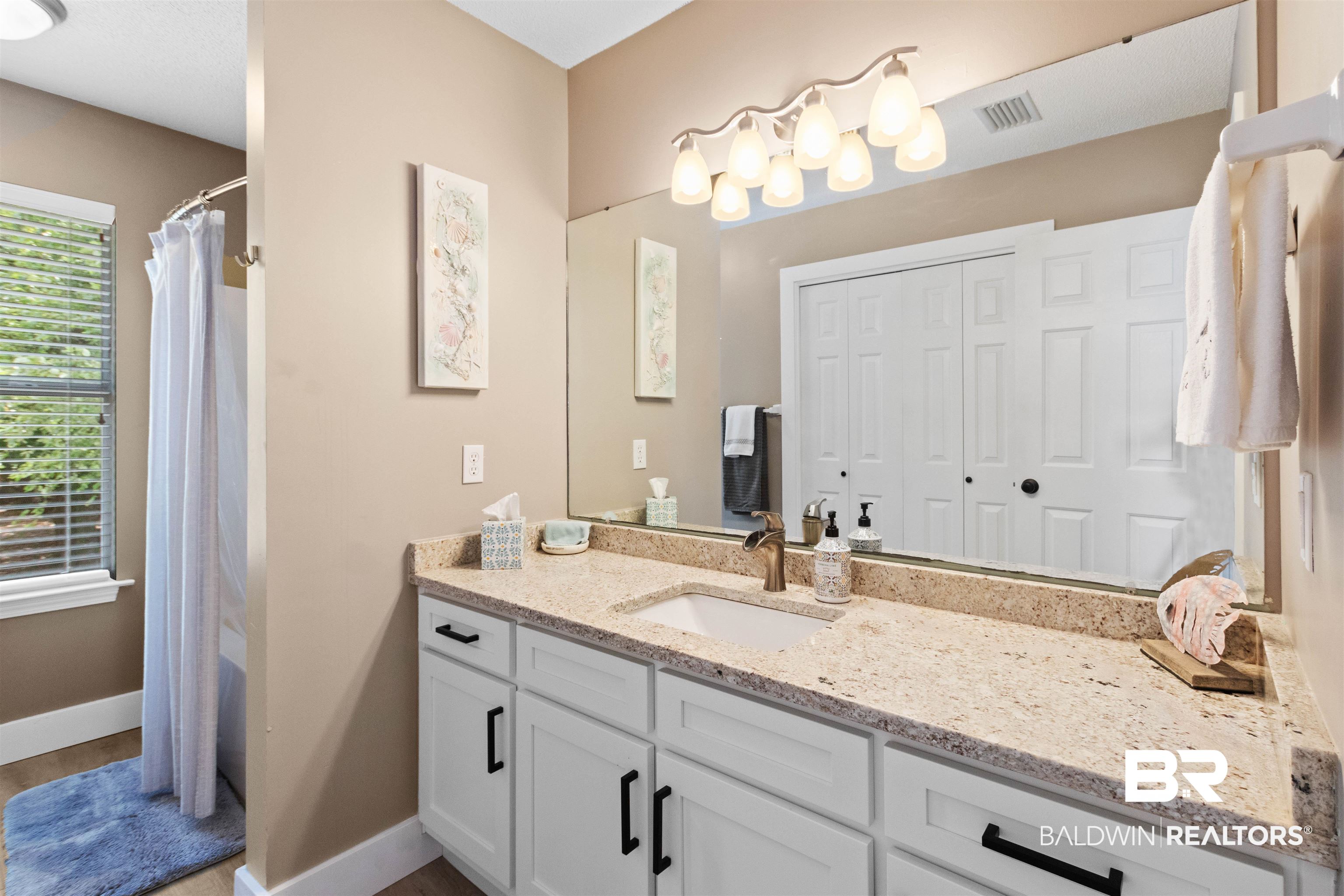 9581 South Bay Street Foley, AL 36535 - Photo 22 of 44 Bathroom featuring a white vanity with black hardware, a light-toned countertop, and a large mirror with overhead lighting