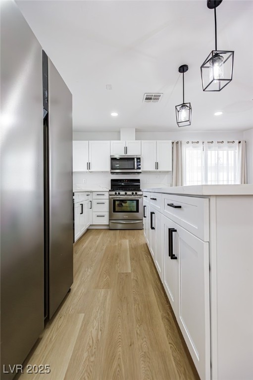 661 Riata Way Las Vegas, NV 89110 - Photo 12 of 30 Kitchen with stainless steel appliances, pendant lighting, light wood-style flooring, white cabinetry, and recessed lighting