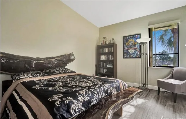 a bed sitting in a bedroom next to a window with chair and couch