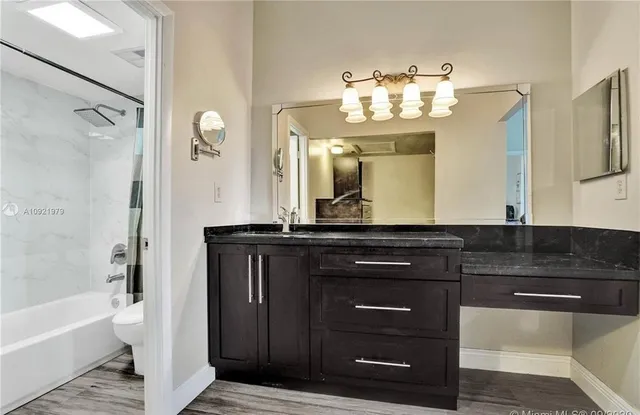 a bathroom with a granite countertop sink a large mirror and a bathtub