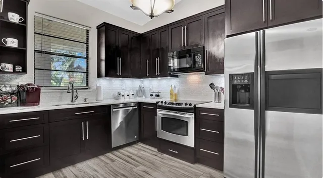 a kitchen with stainless steel appliances granite countertop a refrigerator a sink a stove and oven