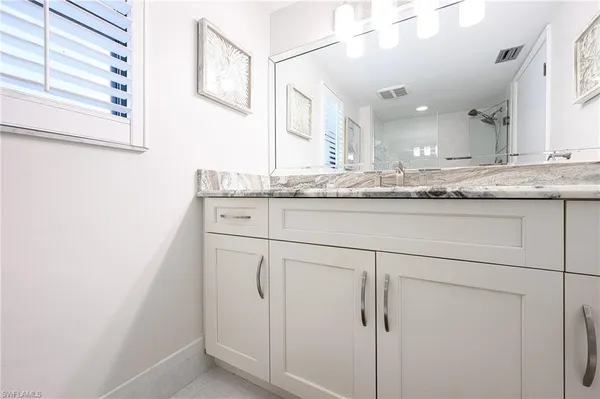 a bathroom with a granite countertop sink and a mirror