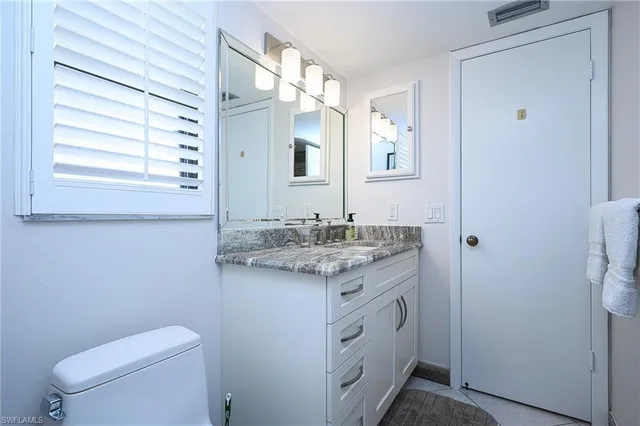 a bathroom with a granite countertop sink toilet and mirror