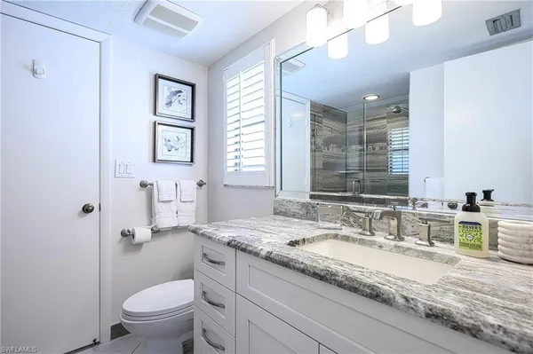 a bathroom with a granite countertop sink a toilet and a mirror