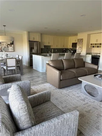 a living room with furniture wooden floor and kitchen view