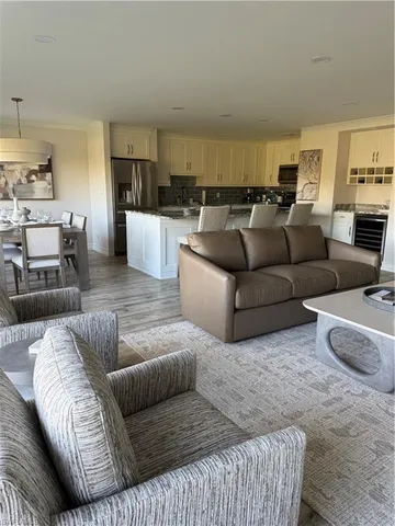 a living room with furniture wooden floor and kitchen view