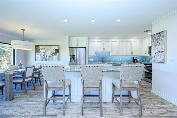 a kitchen with a dining table chairs cabinets and stainless steel appliances