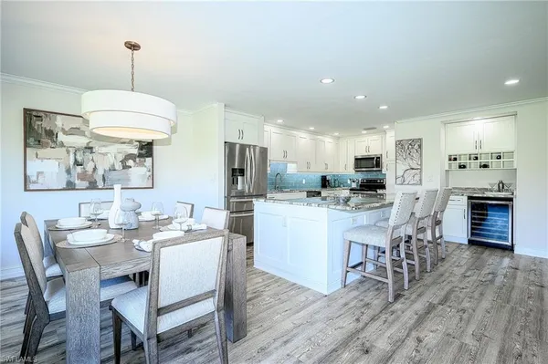 a dining room with stainless steel appliances kitchen island granite countertop a table chairs and a refrigerator