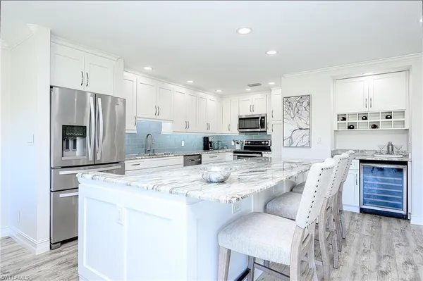 a kitchen with stainless steel appliances kitchen island granite countertop a stove a table and chairs
