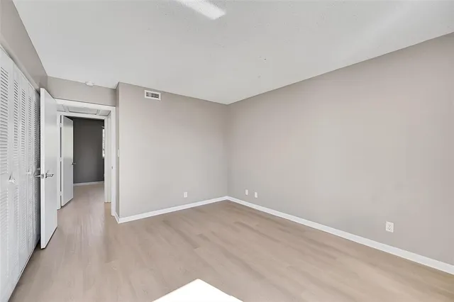 a view of an empty room with wooden floor and closet