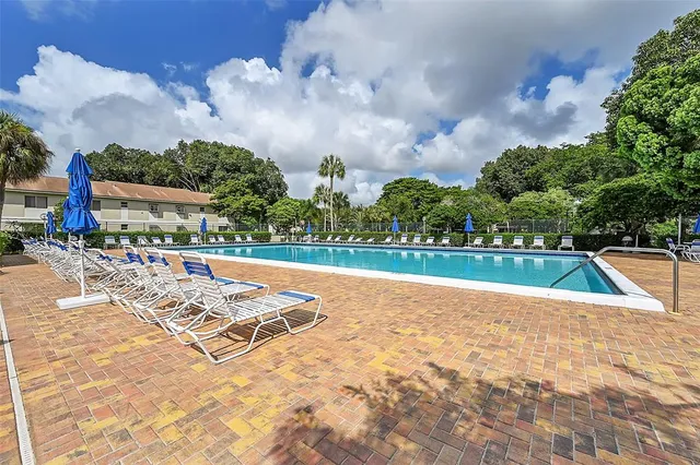 a view of swimming pool with outdoor seating and trees in the background