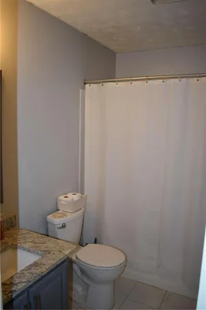 a bathroom with a granite countertop toilet and a sink