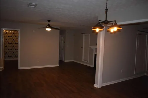 a view of an empty room with wooden floor fan and window