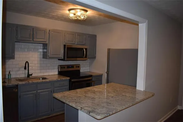 a kitchen with granite countertop stainless steel appliances a sink microwave and stove