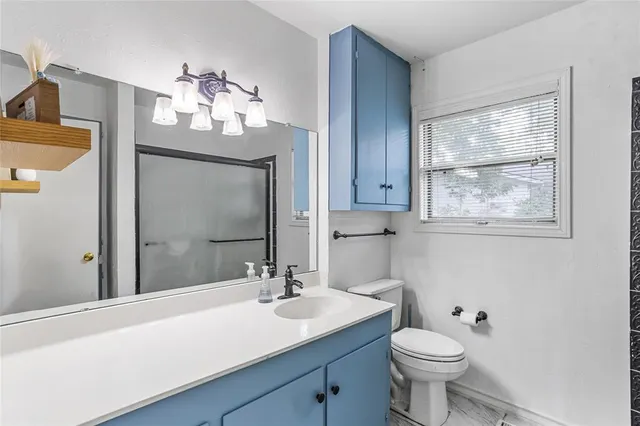 a bathroom with a toilet a sink a mirror a vanity and window
