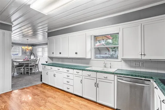 a kitchen with granite countertop a sink stainless steel appliances white cabinets and a window