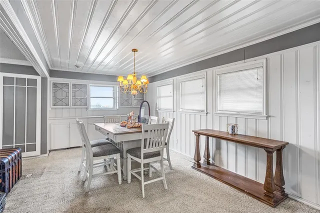 a view of a dining room with furniture a chandelier and large windows