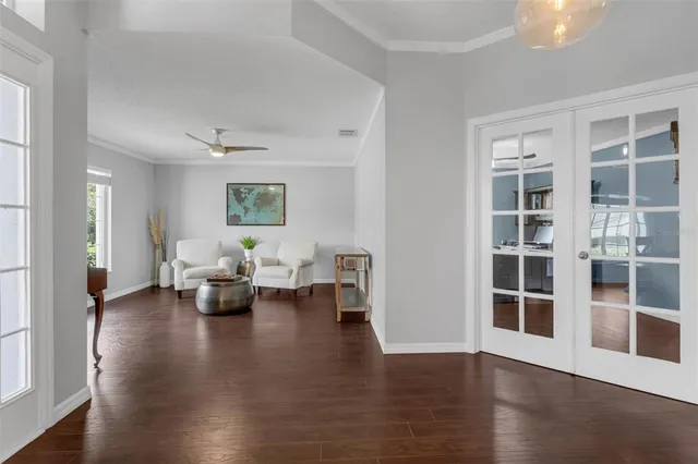 a living room with couches and potted plants with wooden floor
