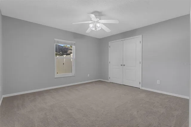 a view of an empty room with chandelier fan