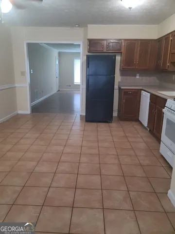 a view of a refrigerator in kitchen and an empty room and window