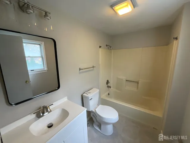 a bathroom with a toilet a sink a tub and mirror