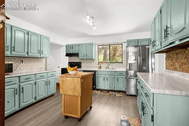 a kitchen with kitchen island granite countertop a sink cabinets and stainless steel appliances