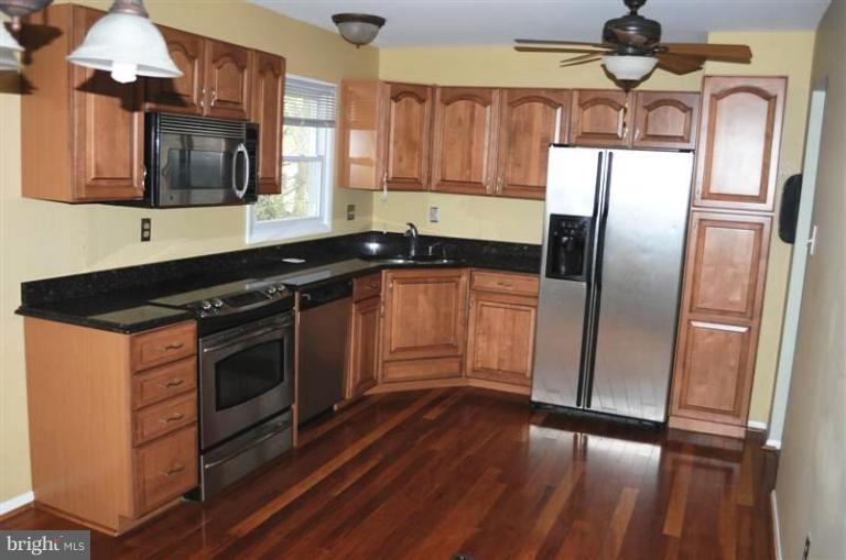 951 Waugh Chapel Road Gambrills, MD 21054 - Photo 11 of 17 a kitchen with stainless steel appliances wooden floor sink and wooden cabinets